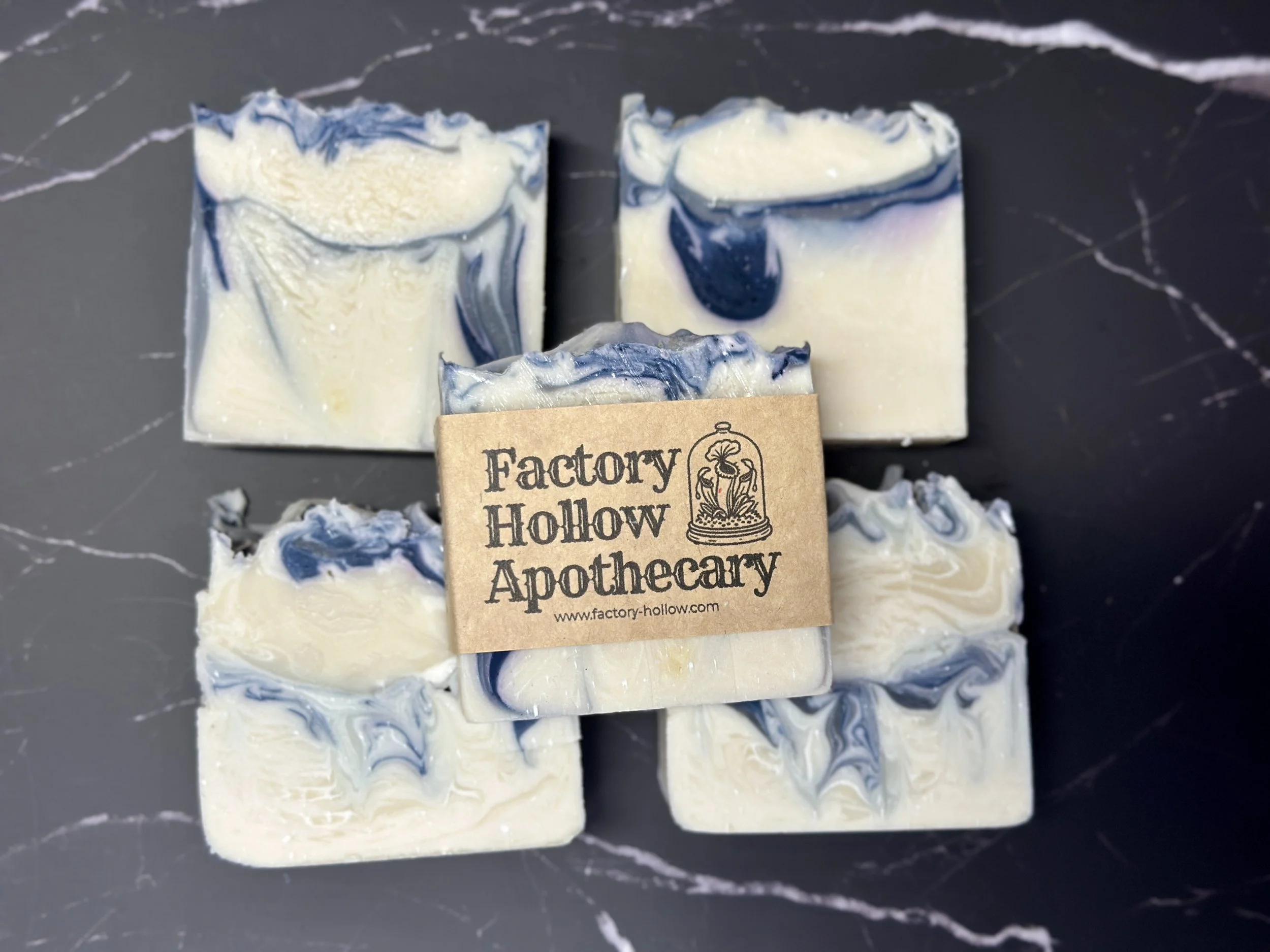 Photo of handcrafted artisan soaps. The soaps are primarily a bright, icy white with threads of deep blue and a tinge of lilac.