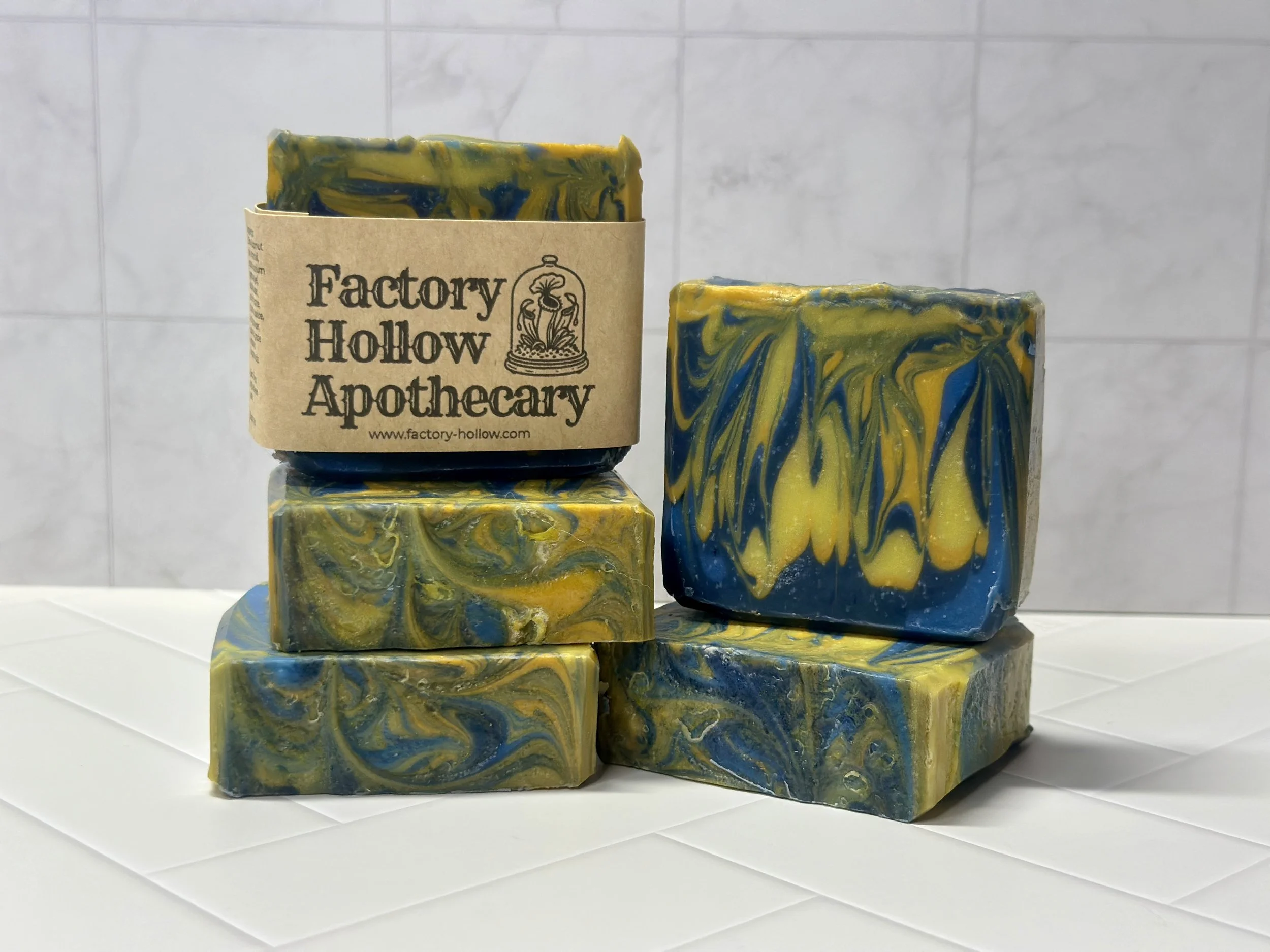 Photo of handcrafted artisan soaps, posed to appeal. The soaps are made of deep blue and bright yellow swirls.