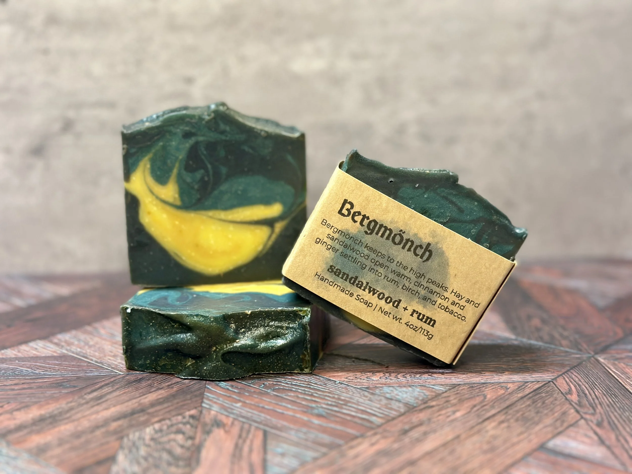 Photo of handcrafted artisan soaps, posed to appeal. The soaps include bright and muted yellows, teal, and deep blue.