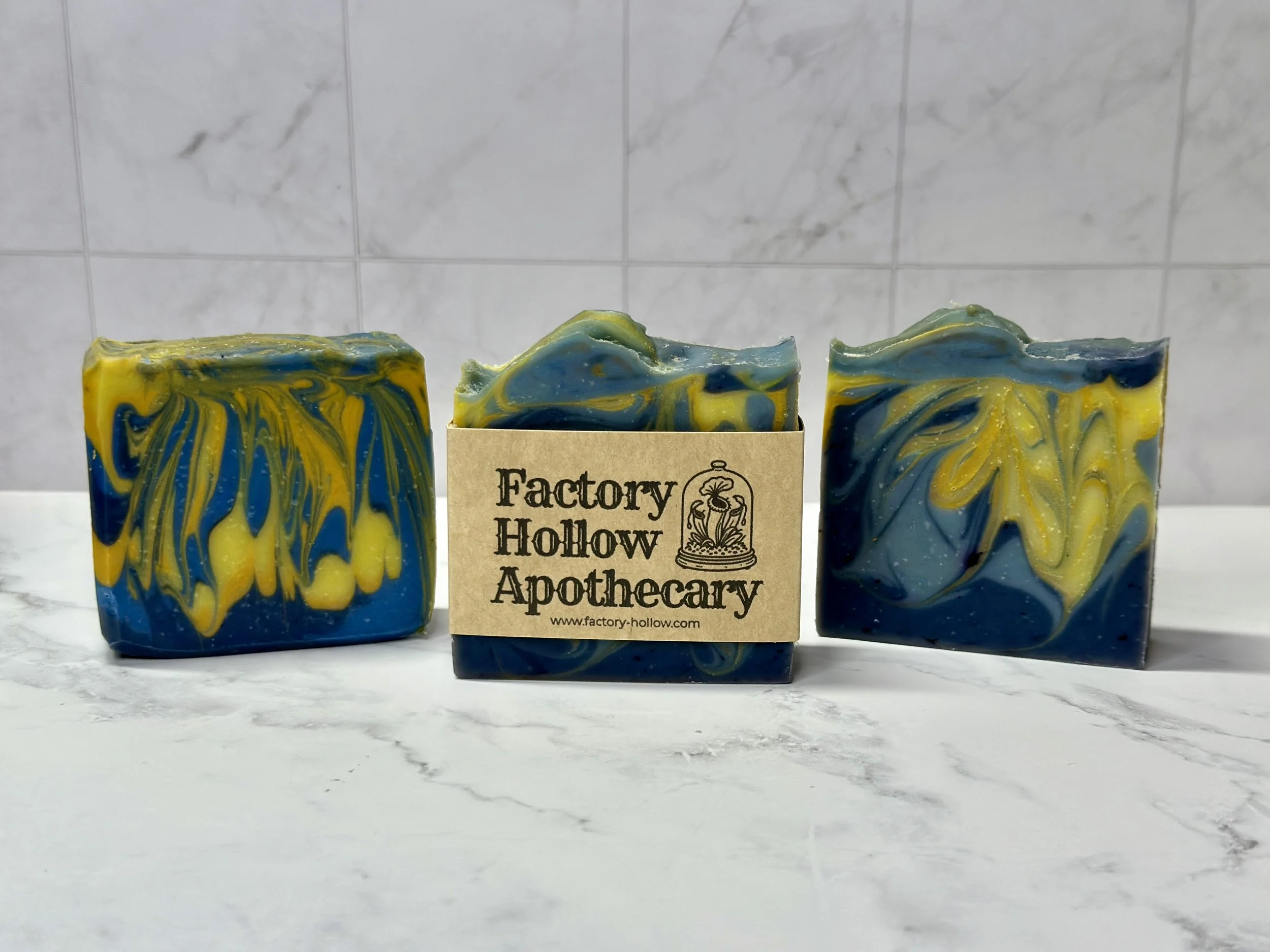 Photo of handcrafted artisan soaps, posed to appeal. The soaps are made of deep blue and bright yellow swirls.
