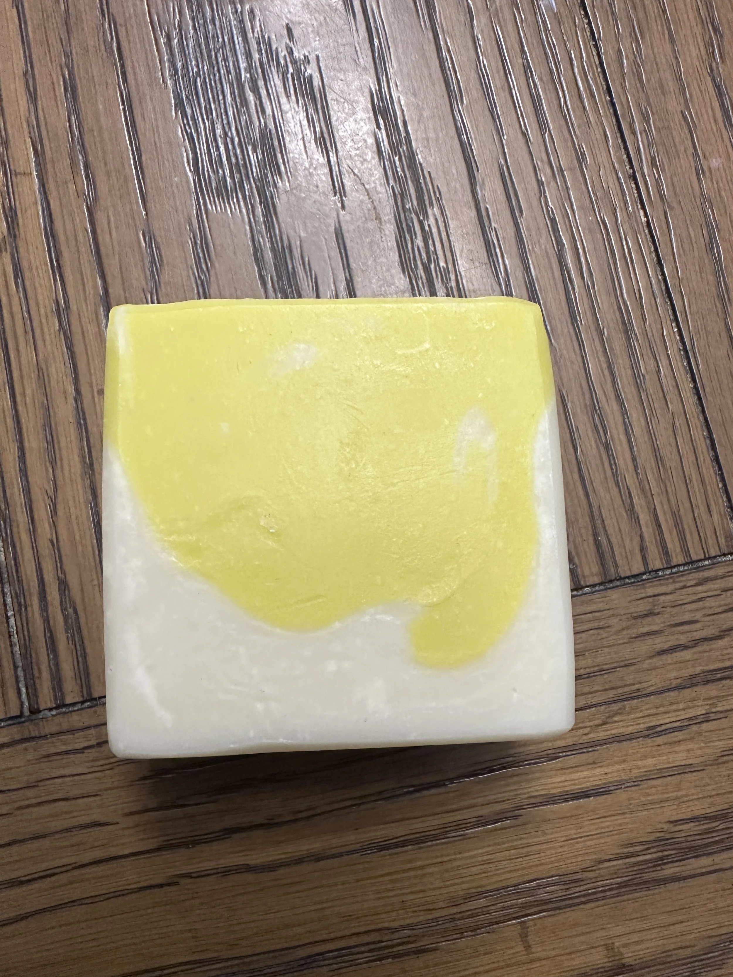 Photo of a handcrafted soap that's about half lemon yellow and half natural off-white.