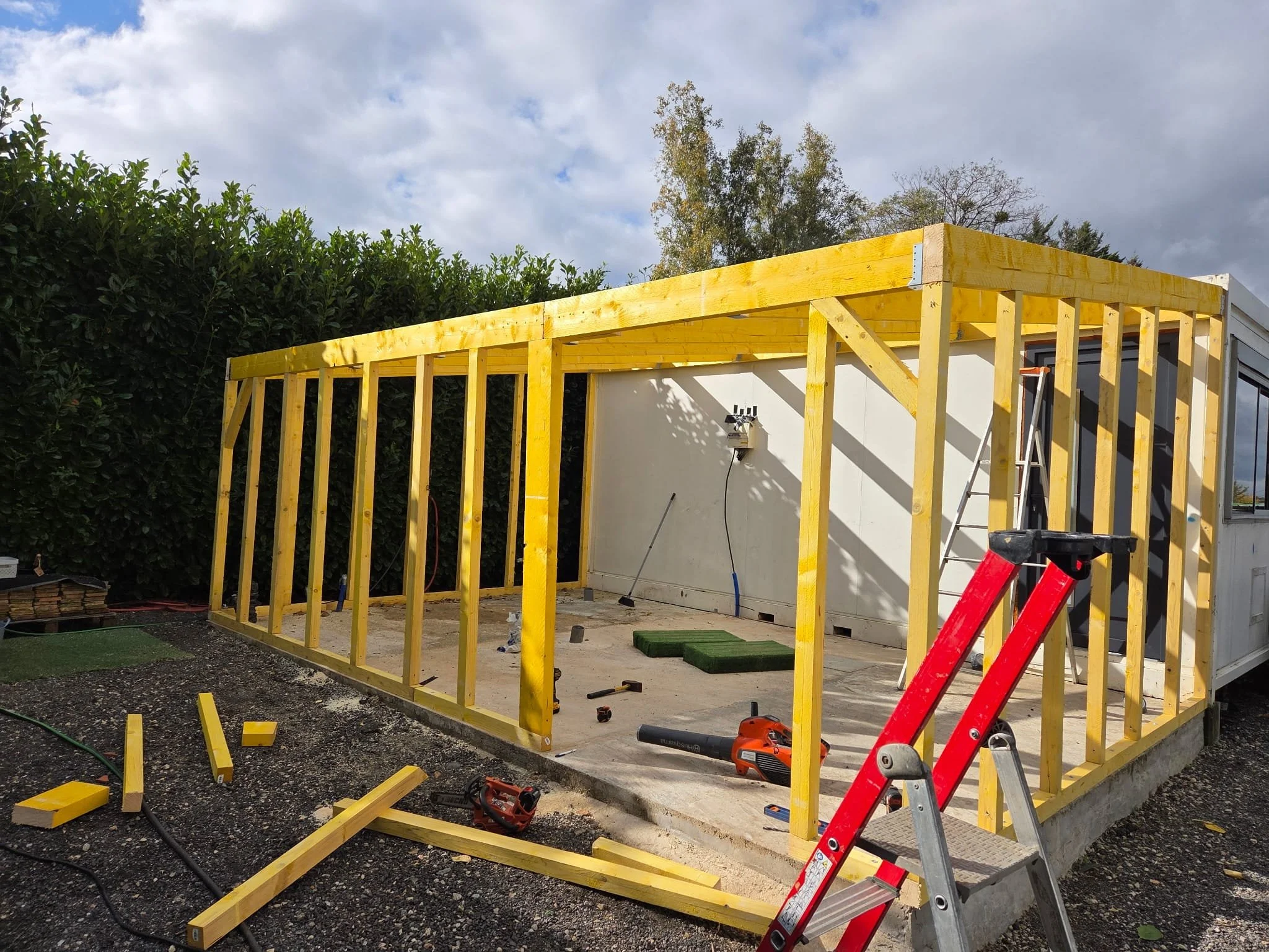 Construction d'une structure en bois pour une extension ou une projection d'une maison, avec outils et matériel visibles.