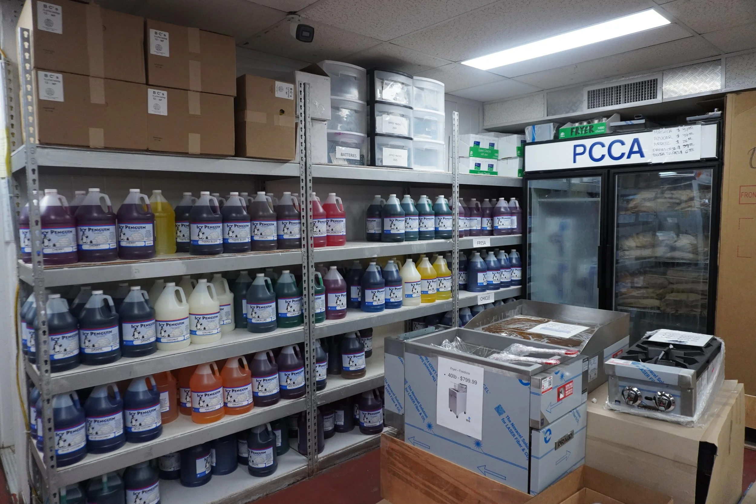 Store shelf stocked with colorful bottles of cleaner or detergent, with some boxes and equipment nearby.