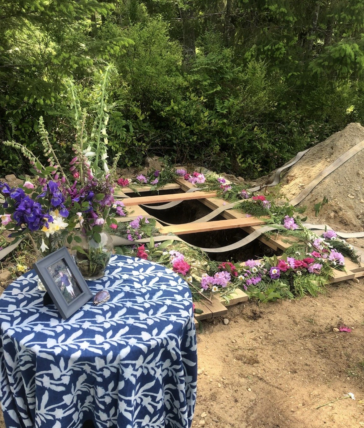 Flowers and greenery arranged around a woodland graveside.