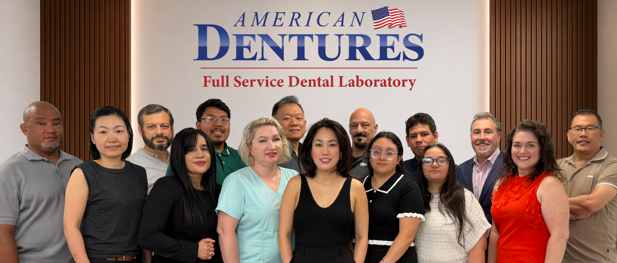 A diverse group of people standing in front of a sign that reads 'American Dentures, Full Service Dental Laboratory,' with an American flag graphic.