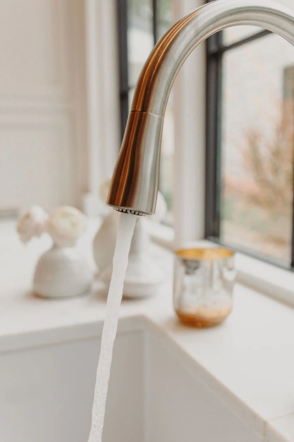 Clean water running from a stainless steel kitchen faucet over a white countertop