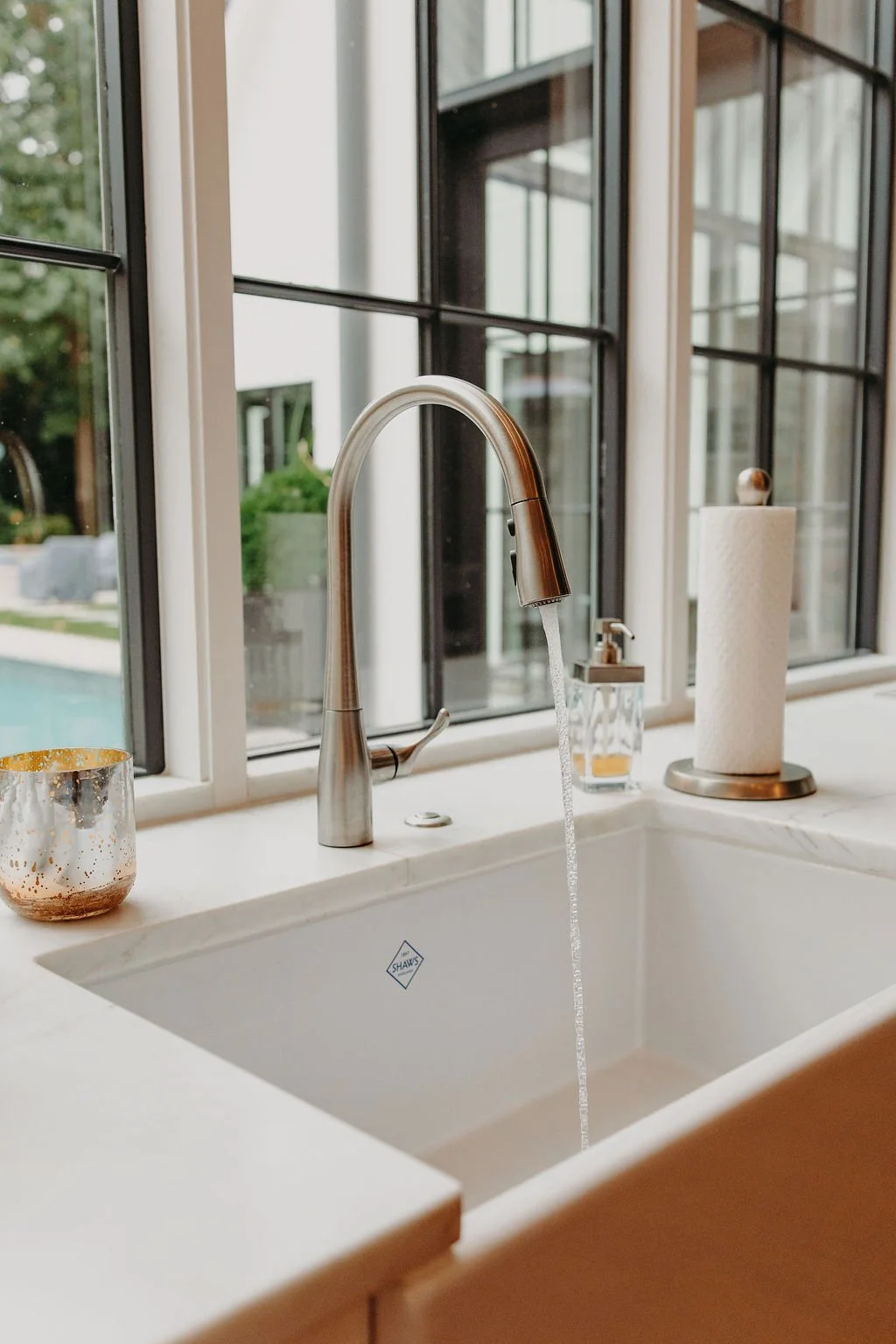 Clean water running from a kitchen faucet in a home with a backyard pool
