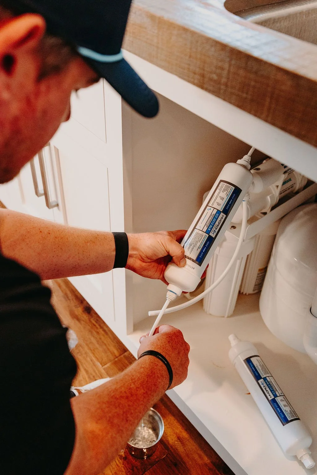 Jared of CLR WTR Solutions installing a reverse osmosis system under a kitchen sink