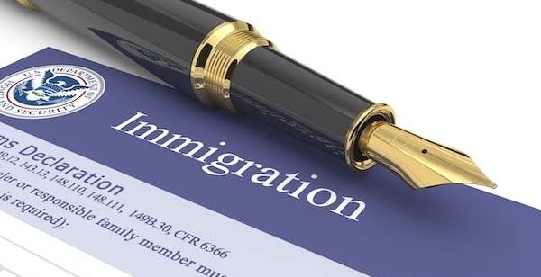 A resume with the heading 'Immigration' and a gold and black fountain pen resting on it.