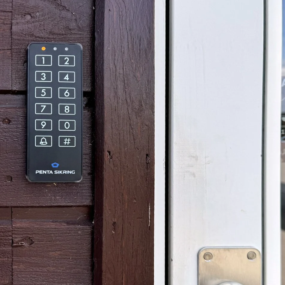 Nøglefri adgangskontrolpanel monteret på trævægsramme ved dør.