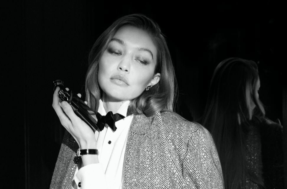 Black and white photo of a woman holding a gun to her head, dressed in formal attire, with another woman reflected in the background.