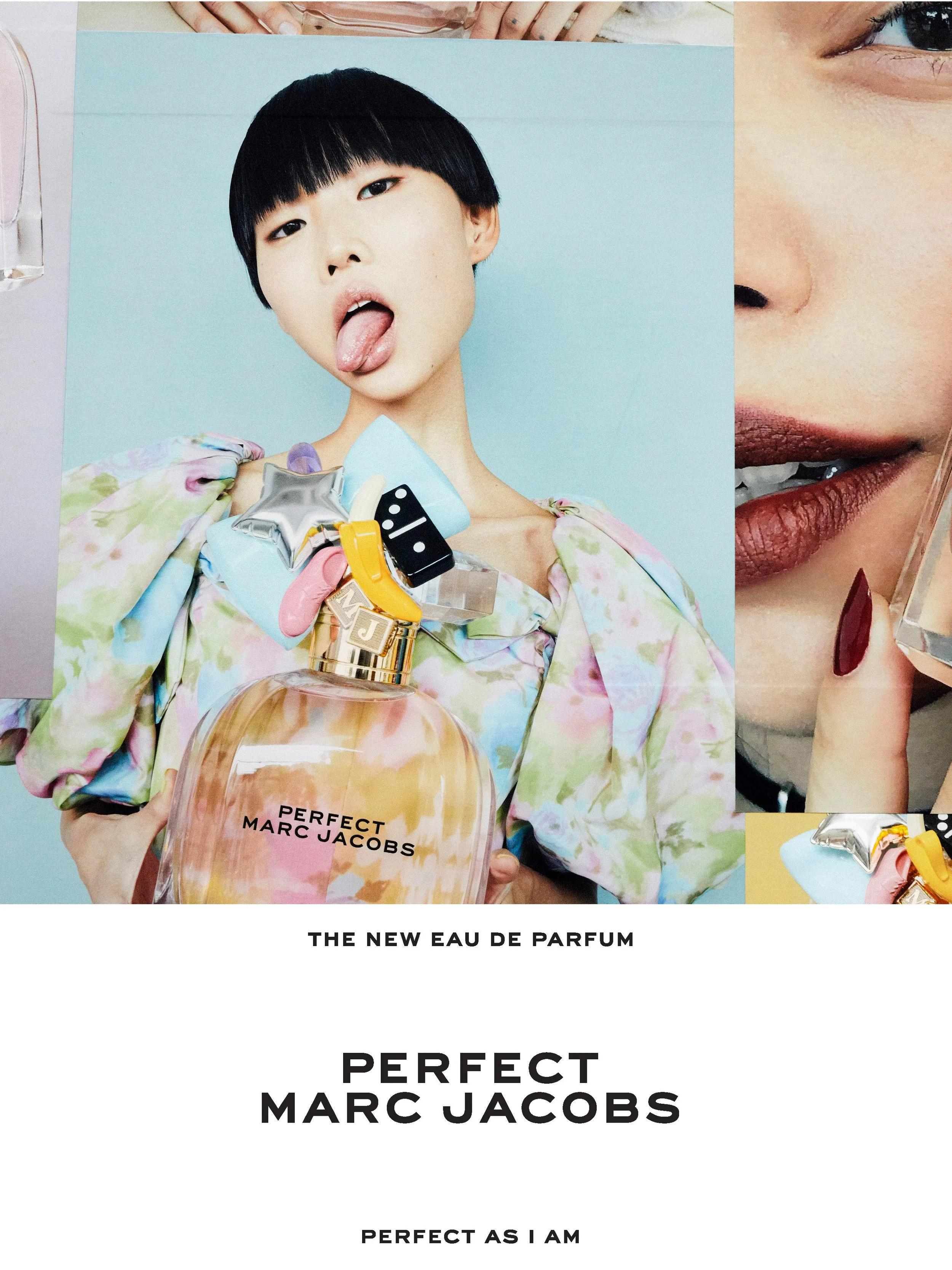 Poster featuring a young woman with short black hair sticking her tongue out, holding a bottle of Marc Jacobs perfume labeled "PERFECT" with various colorful accessories attached. The background is a solid pastel blue, with promotional text for the n