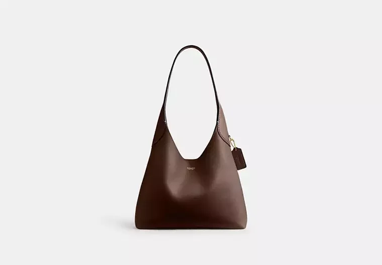Brown leather handbag with a shoulder strap and a small attached tag on the side