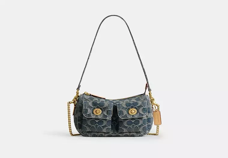 A handbag with a black strap and gold accents, featuring a dark gray pattern and two front pockets with gold buttons.