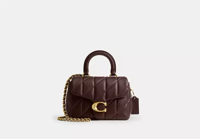 A small quilted dark brown leather handbag with a top handle and a gold chain strap, featuring a gold 'C' emblem on the front.