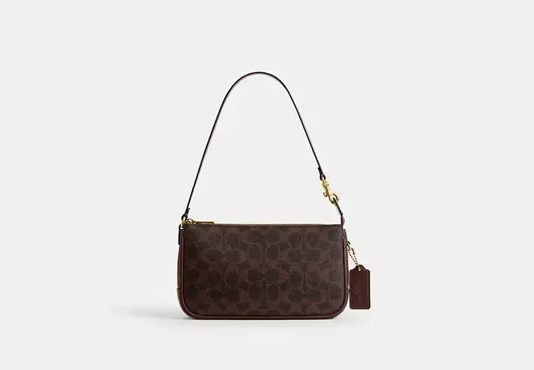 Brown designer handbag with a pattern, hanging from a strap with a small attached tag, set against a plain light background.