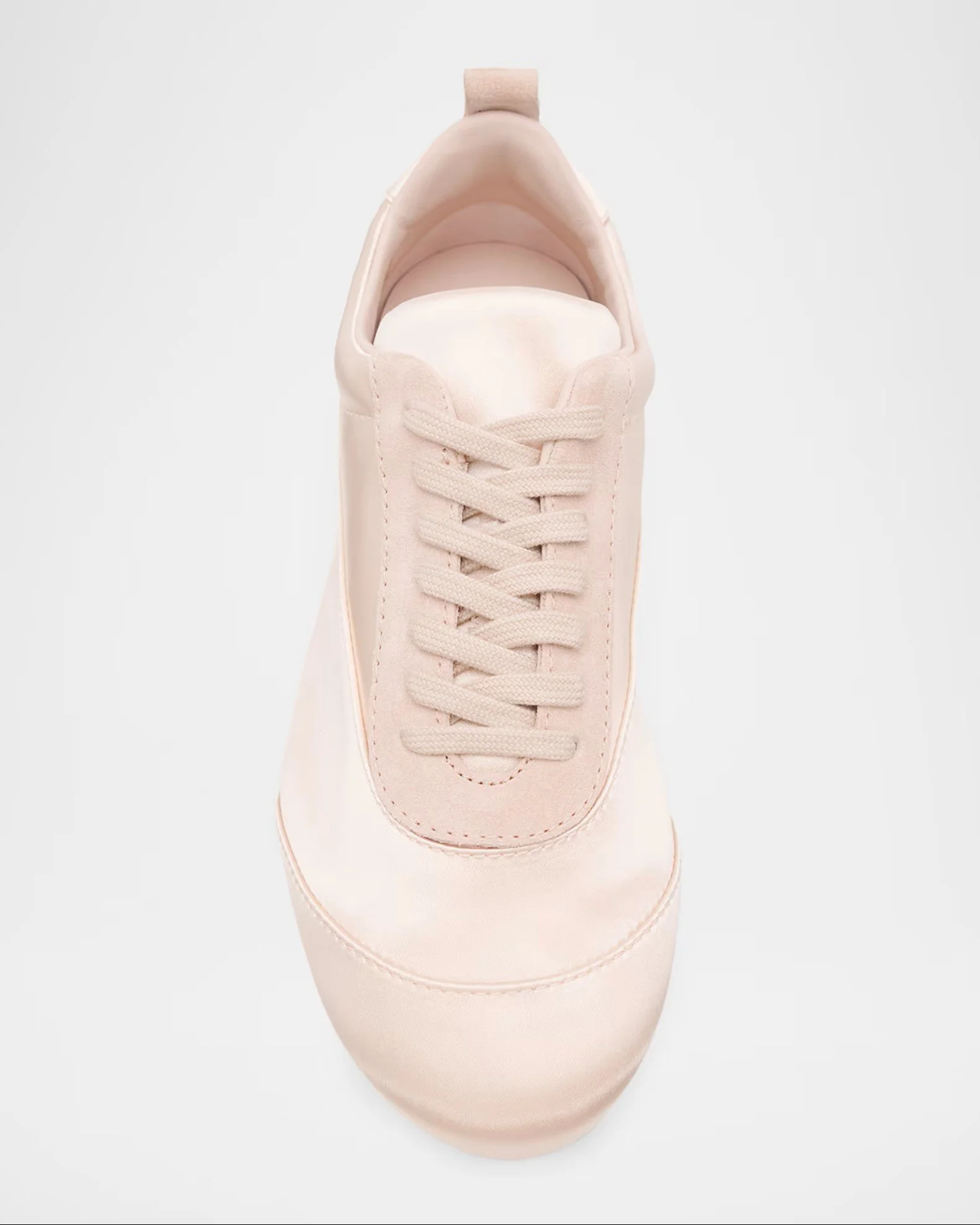 A close-up view of a light pink sneaker with beige laces, taken from above on a white background.