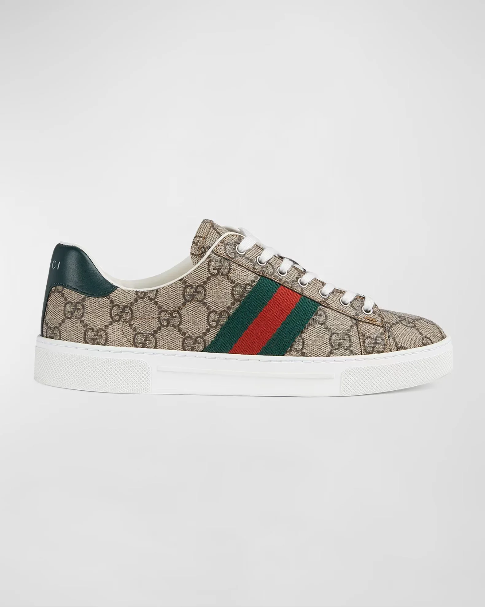 Close-up of a designer sneaker with Gucci logo and signature GG pattern, featuring green and red side stripes, white laces, and a white sole.