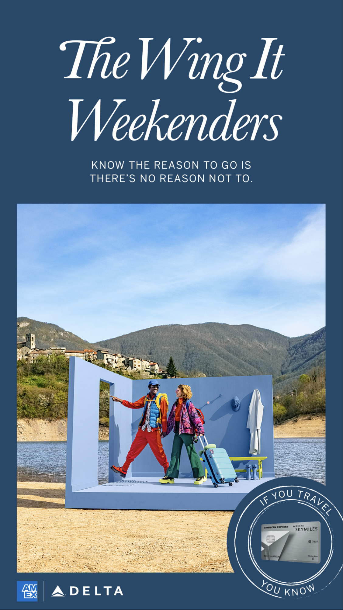 Travel advertisement showing two tourists with rolling suitcase and backpacks standing in a blue photo booth structure by a lake with mountains in background. The text reads "The Wing It Weekenders" and "Know the reason to go is there's no reason not