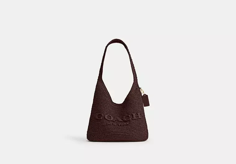 A brown knitted Coach New York handbag with a single handle and a small tag, set against a plain white background.