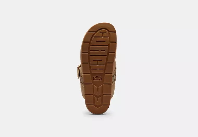 View of a brown children's shoe from the bottom, showing the tread pattern and sole.