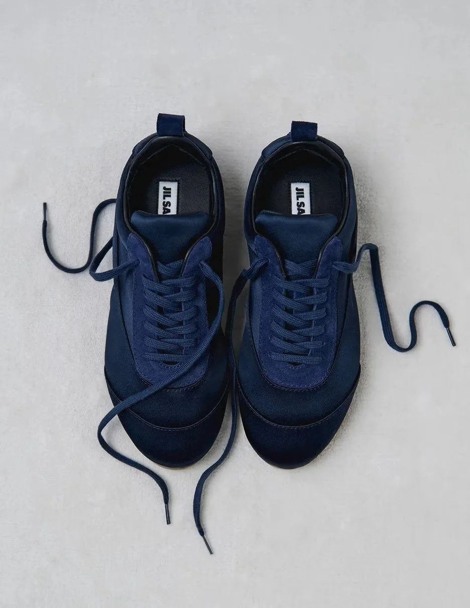 Pair of navy blue athletic sneakers with laces on a light-colored surface.