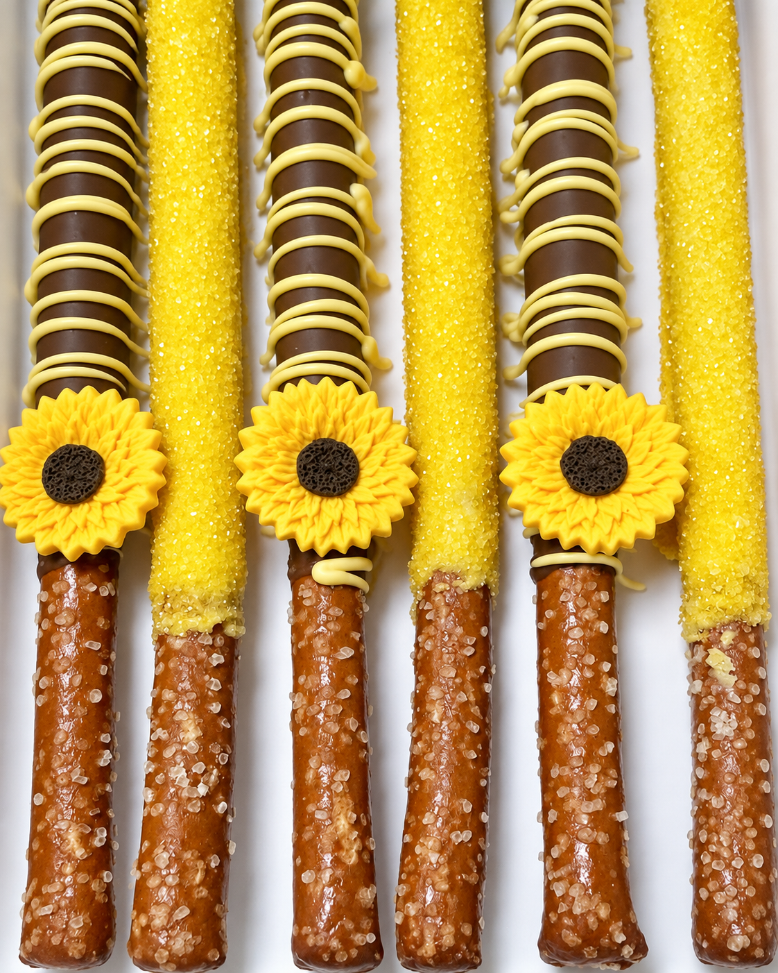 Decorative yellow and brown confections with sunflower-shaped decorations, sugar-coated sticks, and caramel sticks with sugar crystals.