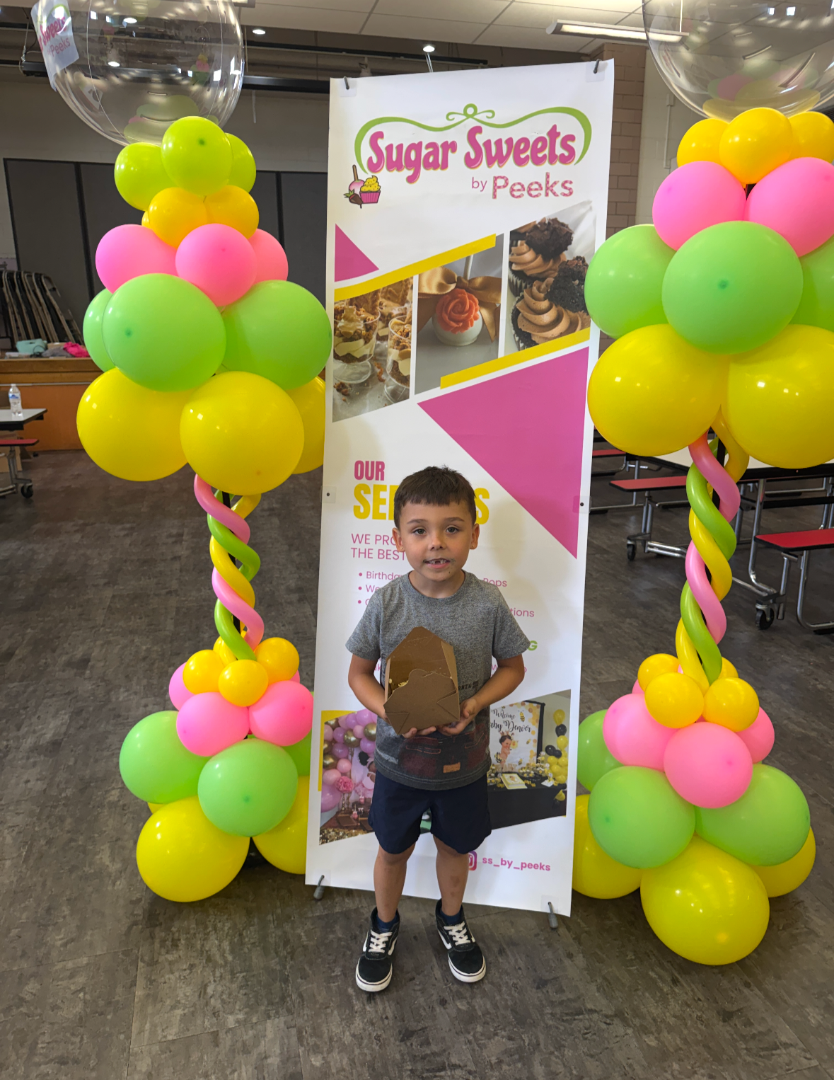 Colorful balloon and a banner fora Sugar Sweets by Peeks class. Yellow, pink, and green balloons with twisted balloon stems, and there are balloons inside transparent globe balloons on the sides. 