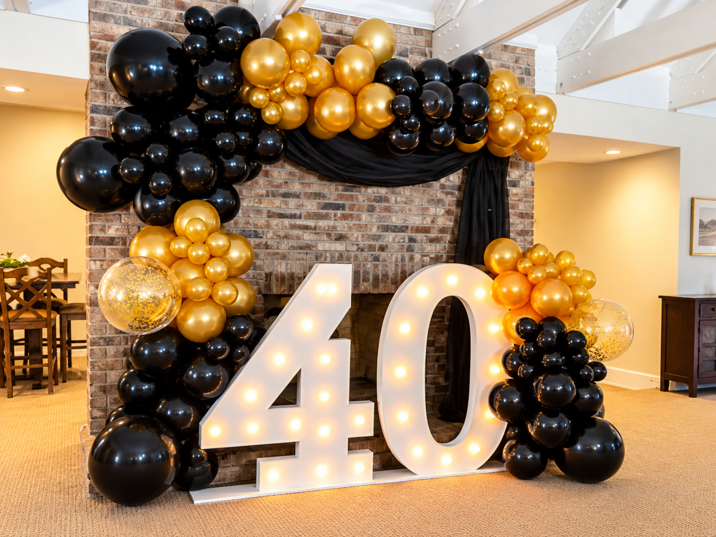 40th birthday celebration decor with large illuminated number 40, gold and black balloons, and a brick fireplace background.