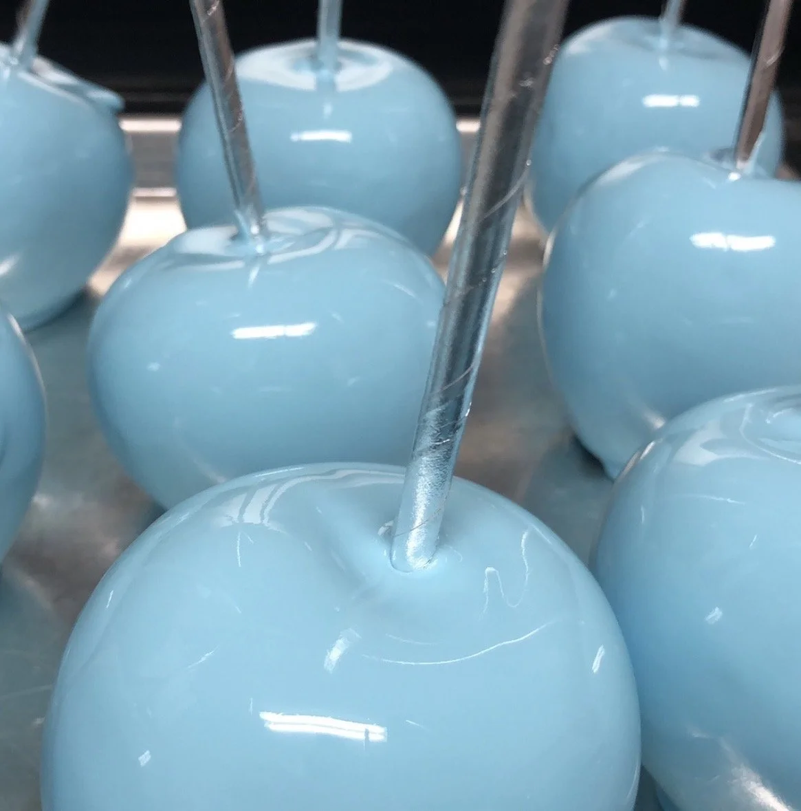 Blue candy apples with shiny glaze and silver sticks.