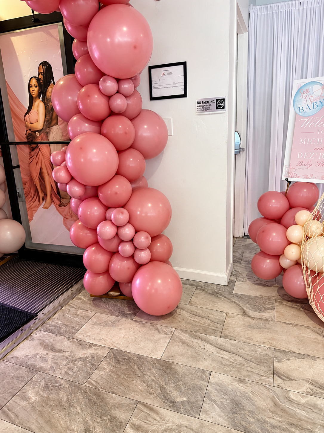 Pink balloon arch and decorations at the entrance of a baby shower event.