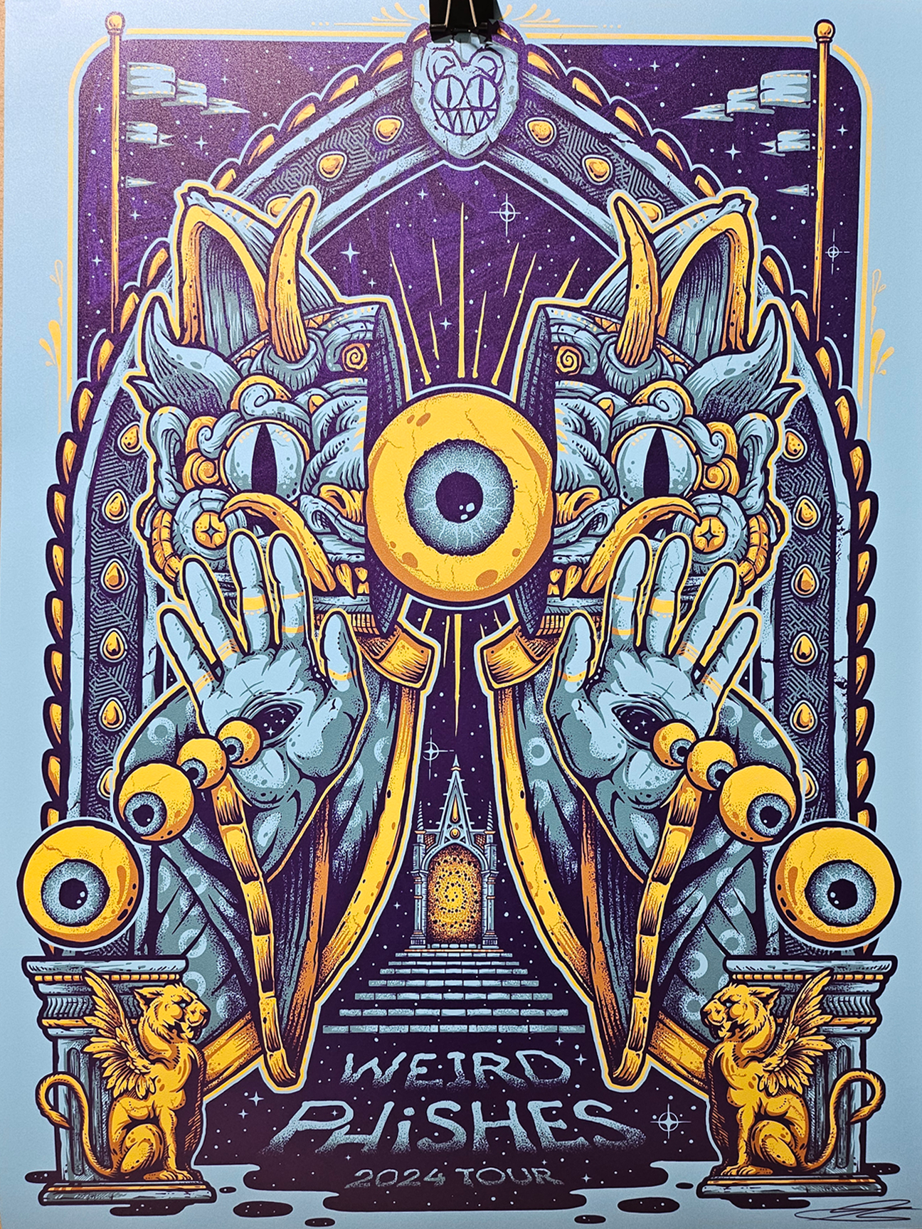 Poster for the "Weird Al" Yankovic 2024 Tour featuring art of a stylized creature with a large eye on its head and horns, holding crescent moons in its hands, and surrounded by decorative elements including lions, stars, and flames.