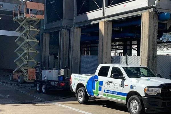 Service truck parked near construction site with lift, under elevated building structure.
