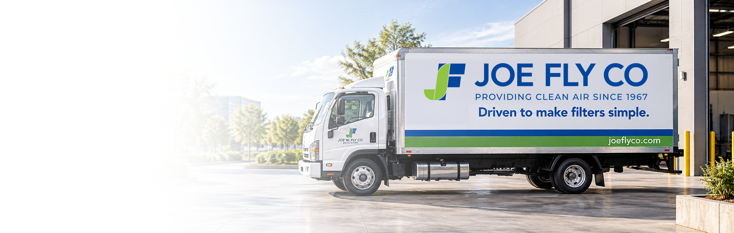 Joe Fly Co. delivery truck parked outside a commercial building, advertising air filtration services and clean air filters.