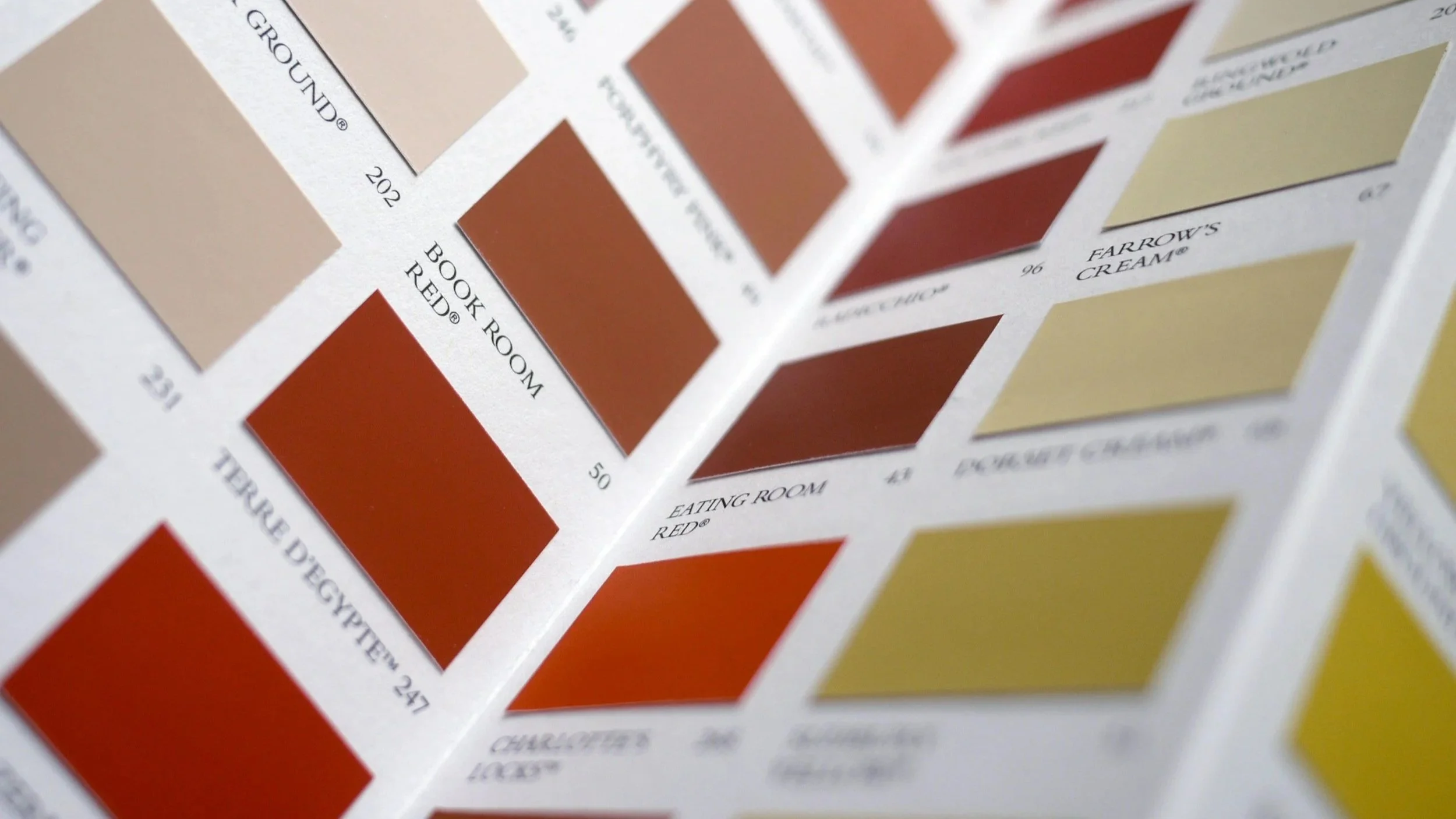 A color swatch chart showing various shades of red, beige, and yellow with labels indicating names and codes, used for selecting paint colors.