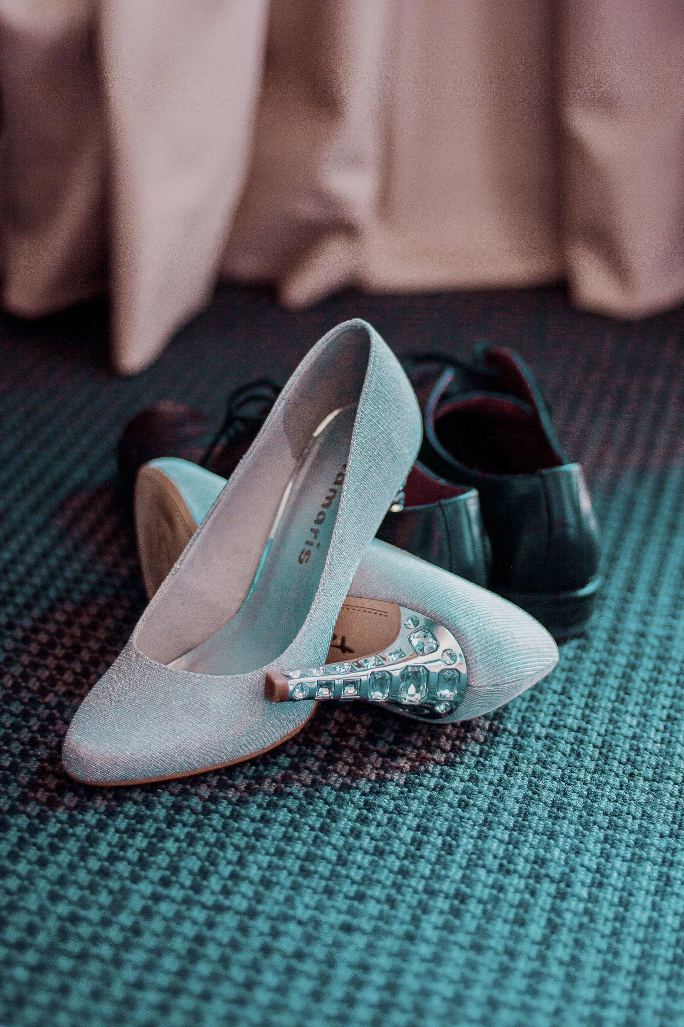 Chaussure à talons hauts blanche avec des cristaux sur le talon, une paire de chaussures en toile blanche sur un tapis gris.