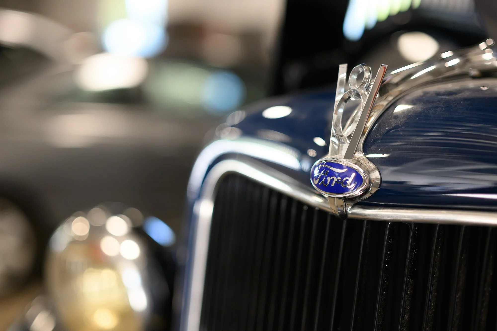 Chrome grille and hood ornament of a vintage Ford in the shop