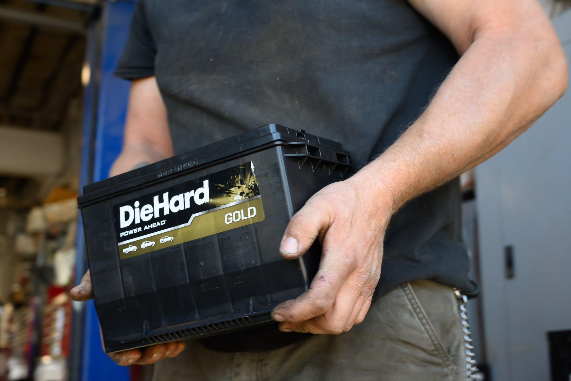 Technician carrying a new car battery