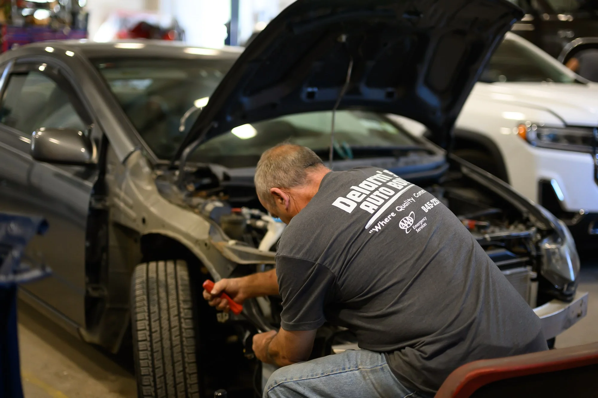 Brian working on a car with the hood up in the Delarm's service bay