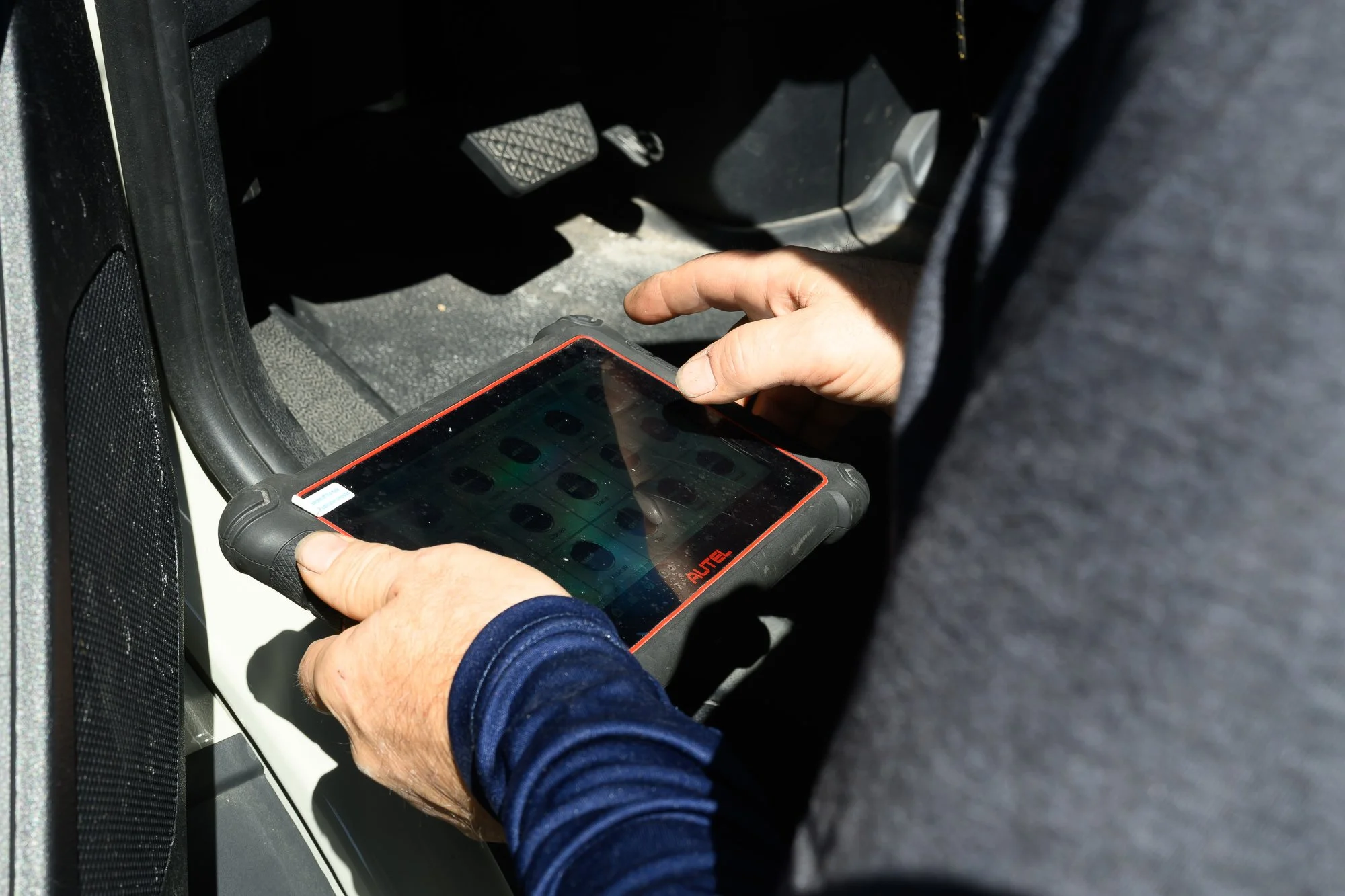 Technician reading a diagnostic scan tool inside a car