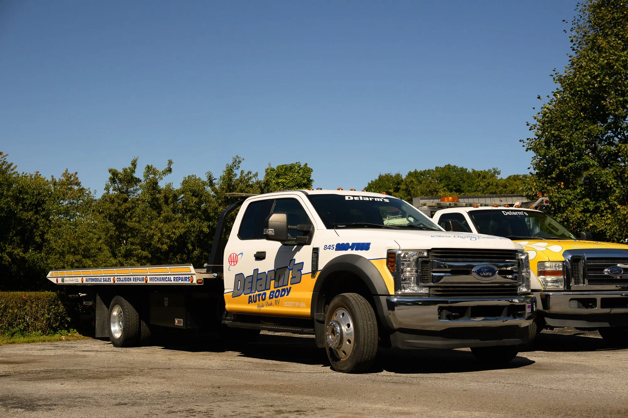 Delarm's flatbed tow truck and pickup parked outside the shop in Hyde Park, NY