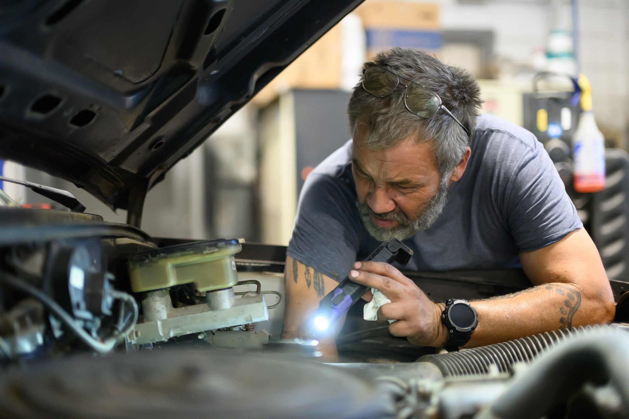 John working under the hood with a flashlight