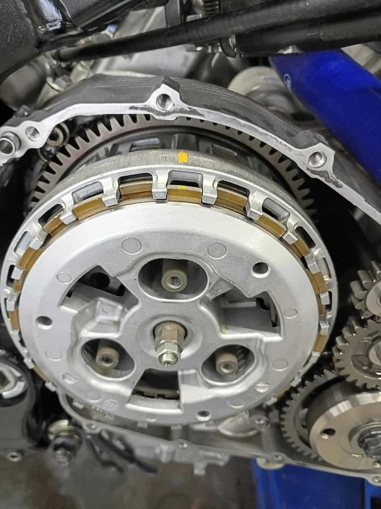Close-up of a motorcycle engine's internal components, showcasing the clutch assembly, gears, and metal parts.