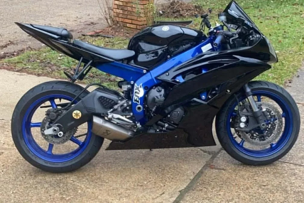 A black and blue Yamaha sport motorcycle parked on a concrete sidewalk.