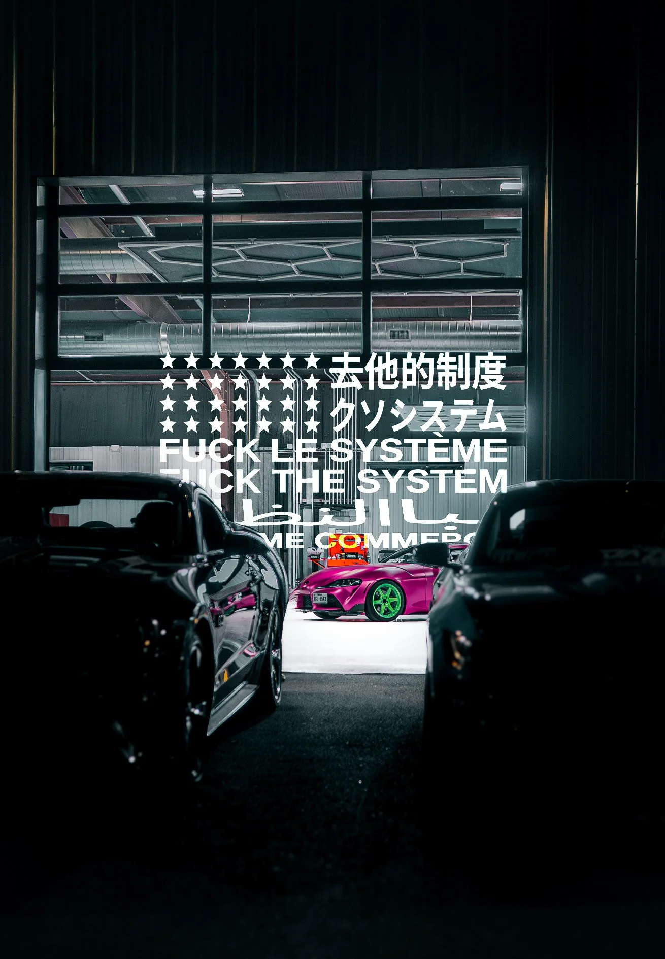 View of a dimly lit parking garage with a brightly colored pink sports car with green rims visible in the background, and black cars in the foreground. A large illuminated sign behind the cars has white text in multiple languages, including English, that reads 'FUCK THE SYSTEM' and similar phrases.