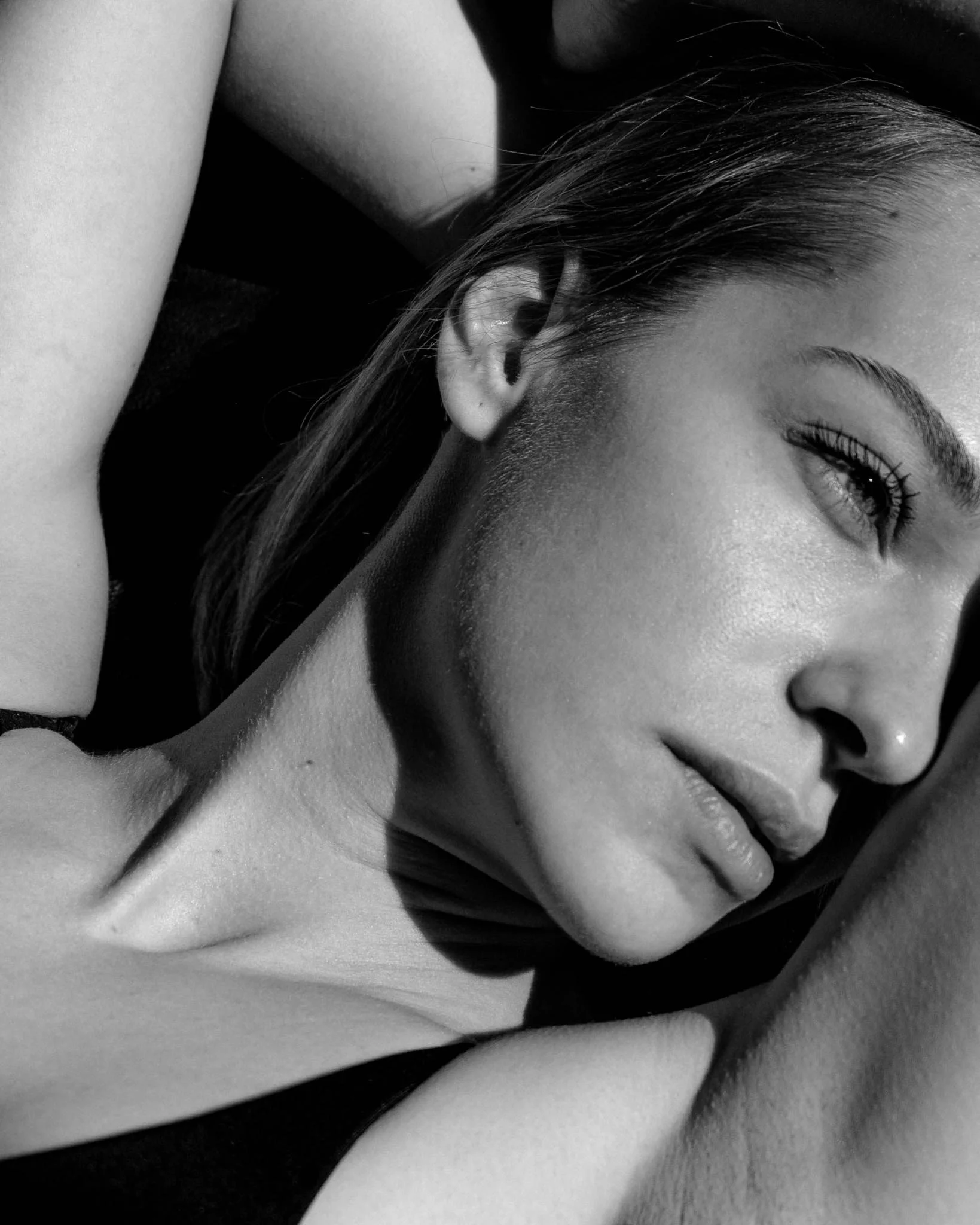 Close-up black and white photo of a woman's face, focusing on her eye, eyebrow, and part of her forehead, with her hair covering part of her face.