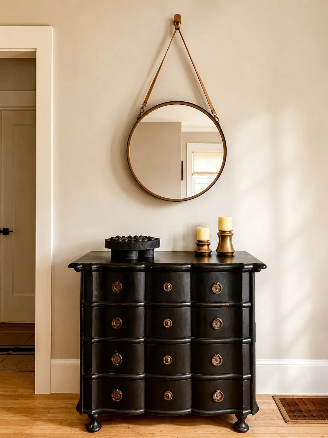 Elegant entryway interior by Aster & Aire featuring a vintage black chest of drawers, statement round mirror and warm layered styling, showcasing approachable and affordable interior design in San Anselmo, Marin County.