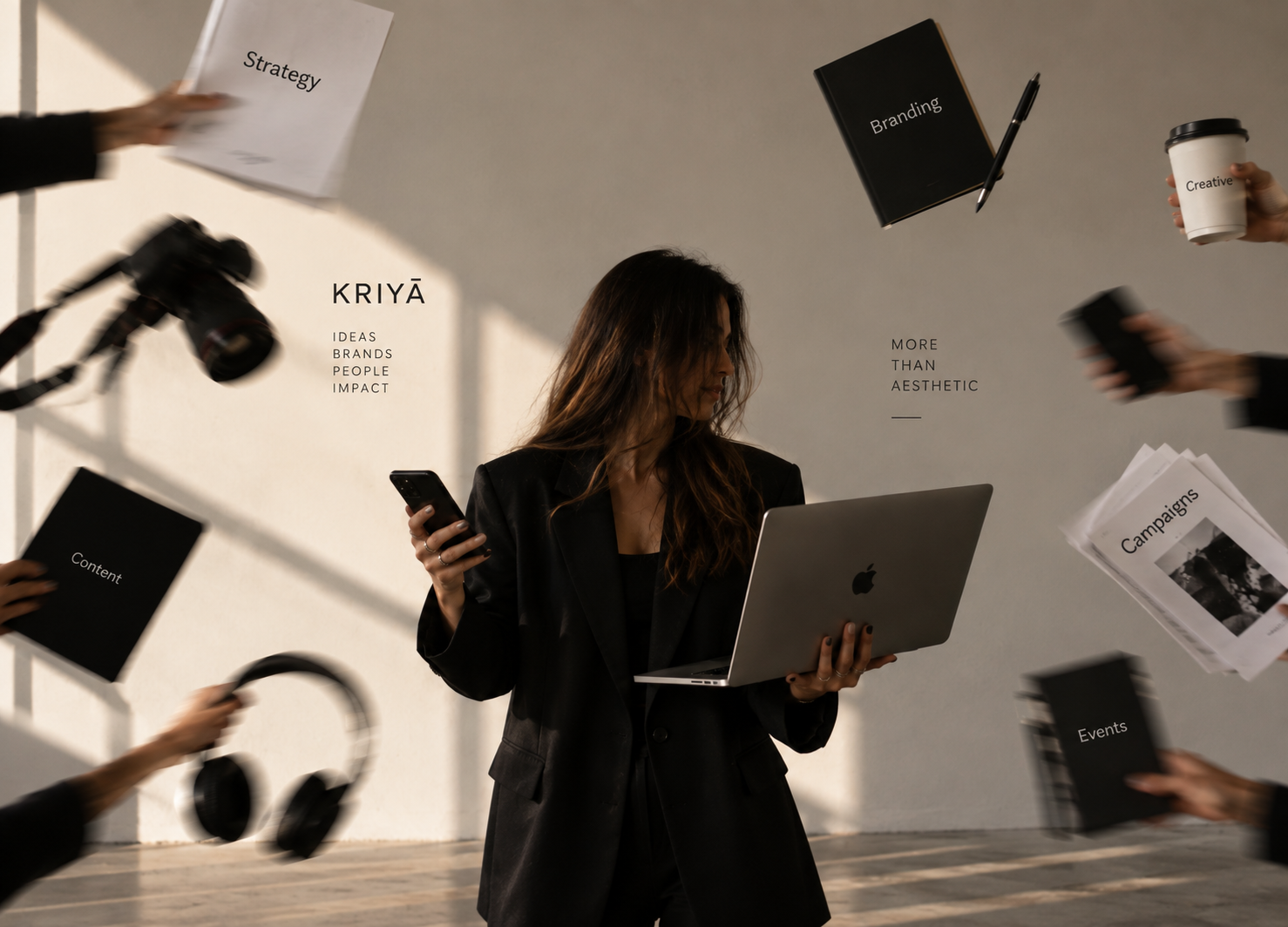 Profissional da Kriyā Projects com portátil rodeada por ferramentas de fotografia, design e marketing, representando um processo criativo multidisciplinar.