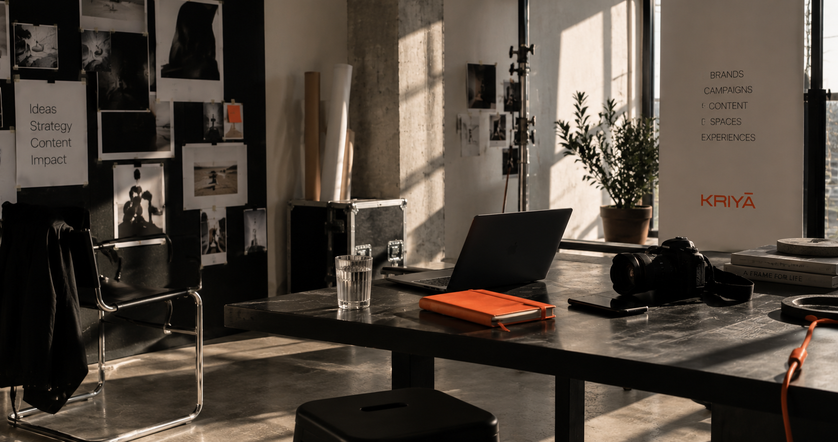 Espaço de trabalho criativo da Kriyā Projects com portátil, câmara e materiais de referência para branding e produção de conteúdo.