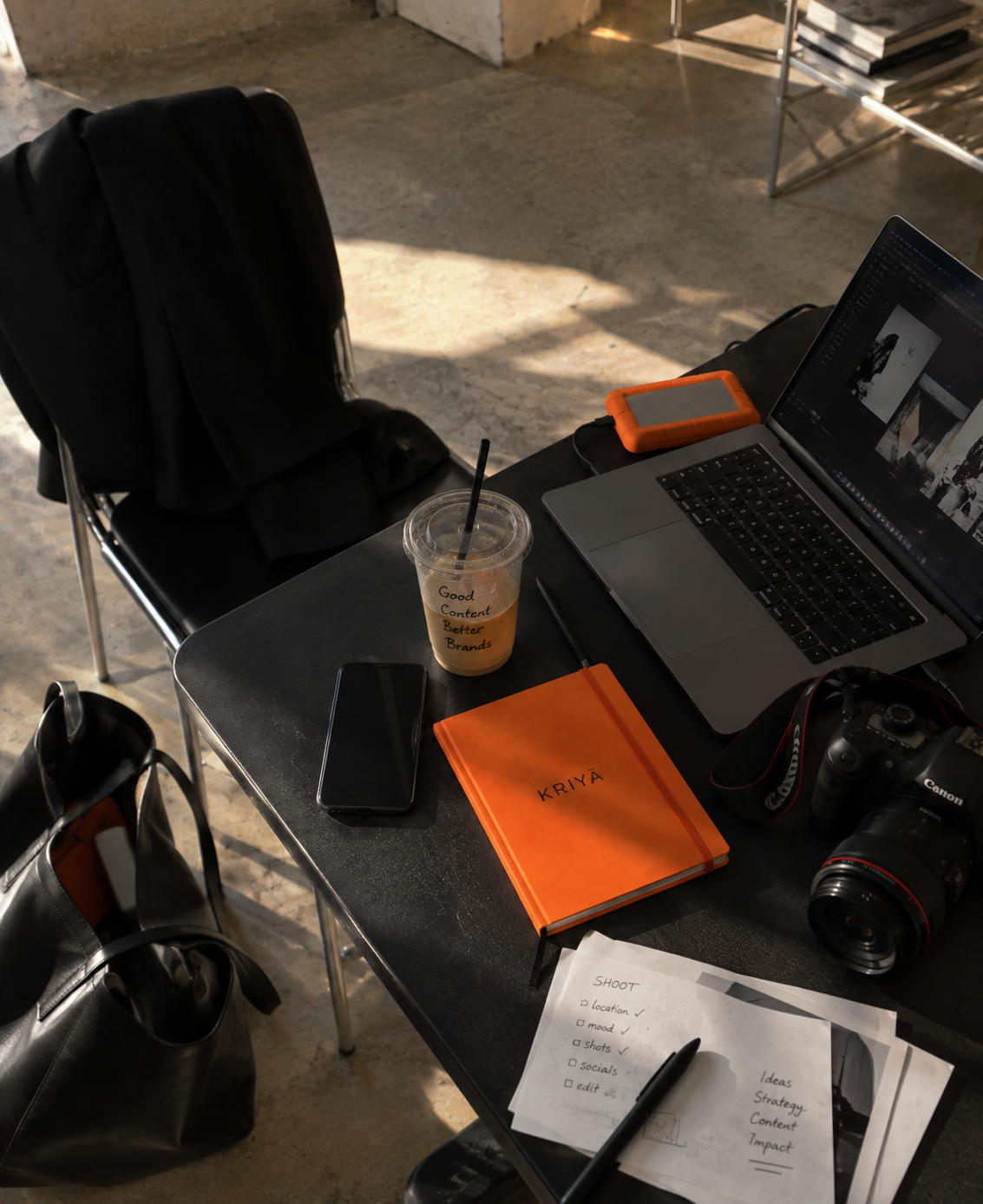 Mesa de trabalho da Kriyā Projects com portátil e materiais criativos durante o desenvolvimento de projetos de branding e comunicação.